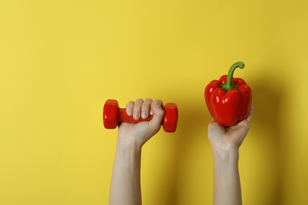 Hand holding a weight and hand holding a bell pepper