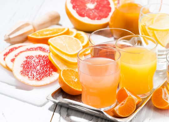sliced fruit and cups of juice