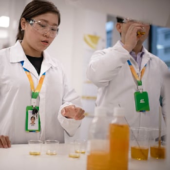 Two ADM scientists in a lab testing samples of an orange liquid 