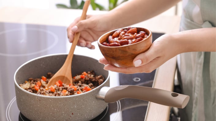 Woman cooking traditional chili con carne in kitchen