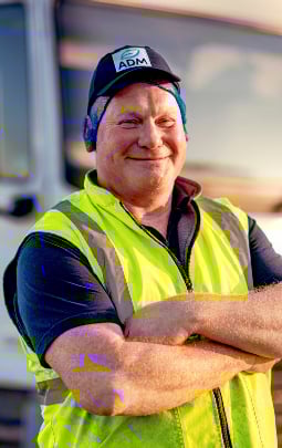 An ADM driver stands in front of his truck 