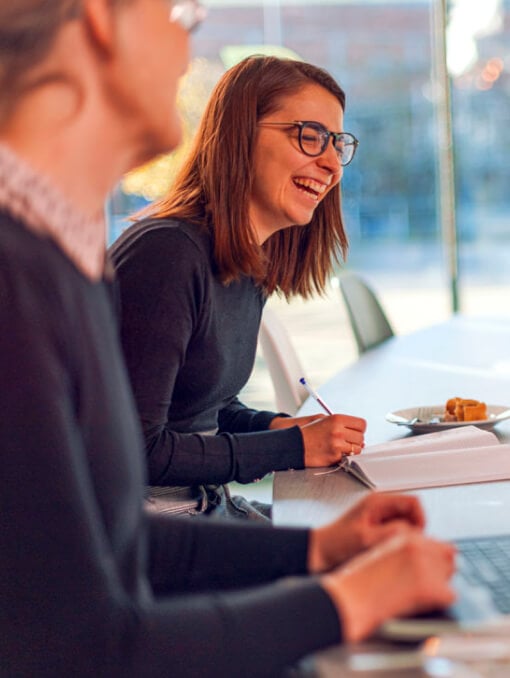 A woman in a corporate office laughing and taking notes