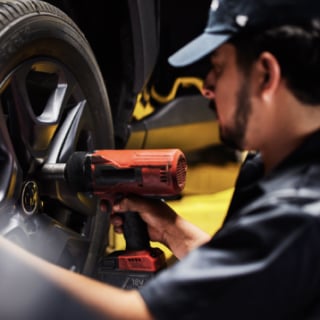 A person working on a vehicle tire with a power tool