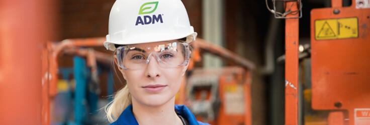 A female engineer at work wearing safety glasses and an ADM hard hat