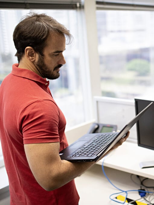 A corporate office employee in an office setting holding a laptop