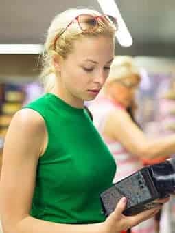 woman reviewing product label in grocery store