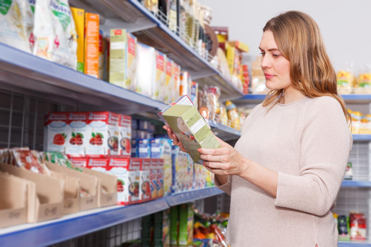 Woman reading ingredients on food package in grocery store