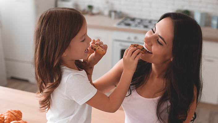 Mother and Daughter in the kitchen eating healthy cookies together