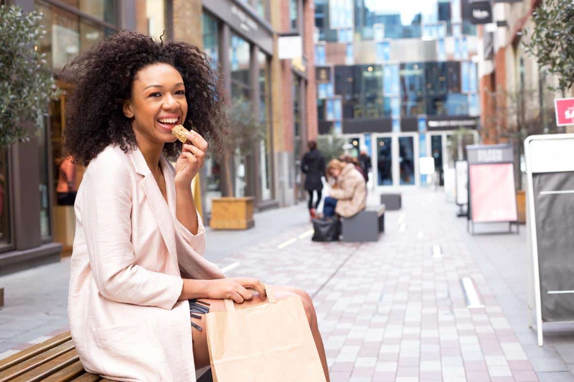 Happy young woman having a healthy snack while sitting on a nice street