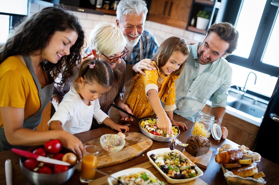 A multi-age, multi-ethnic family enjoying a colorful, delicious-looking meal