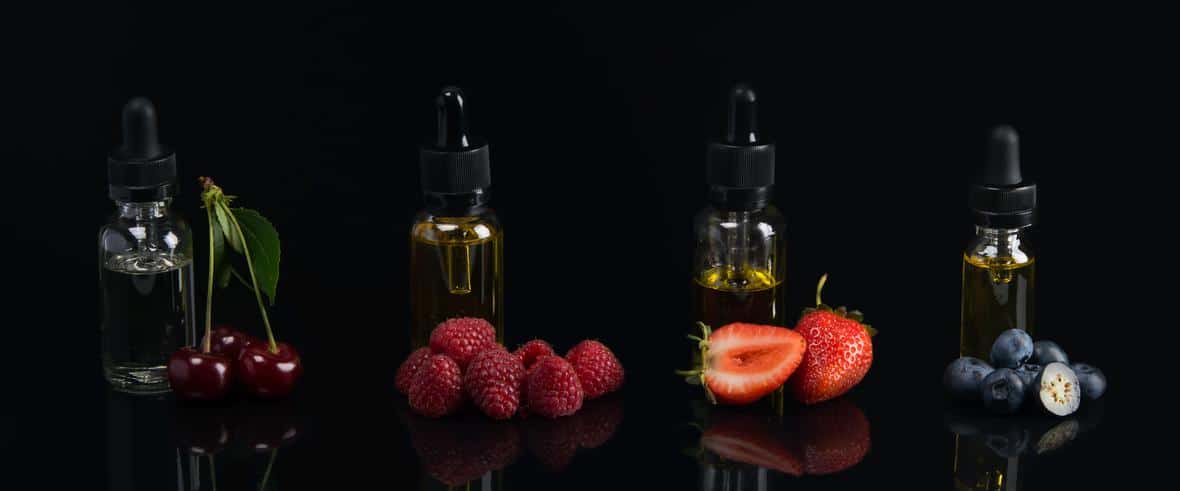 Flavors in glass bottles with fruits beside them