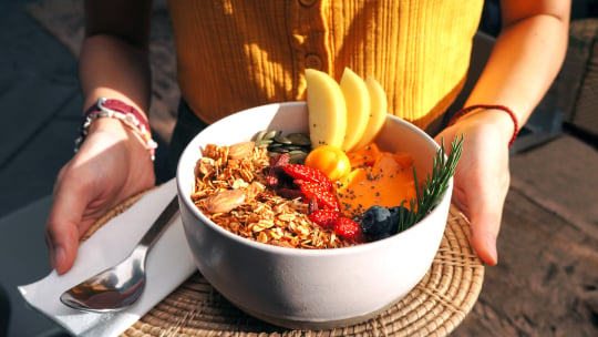 woman holding bowl of fruit and grains