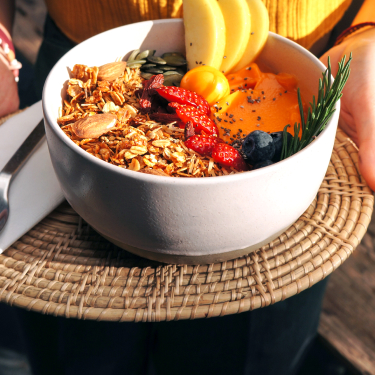 woman holding bowl of fruit and grains