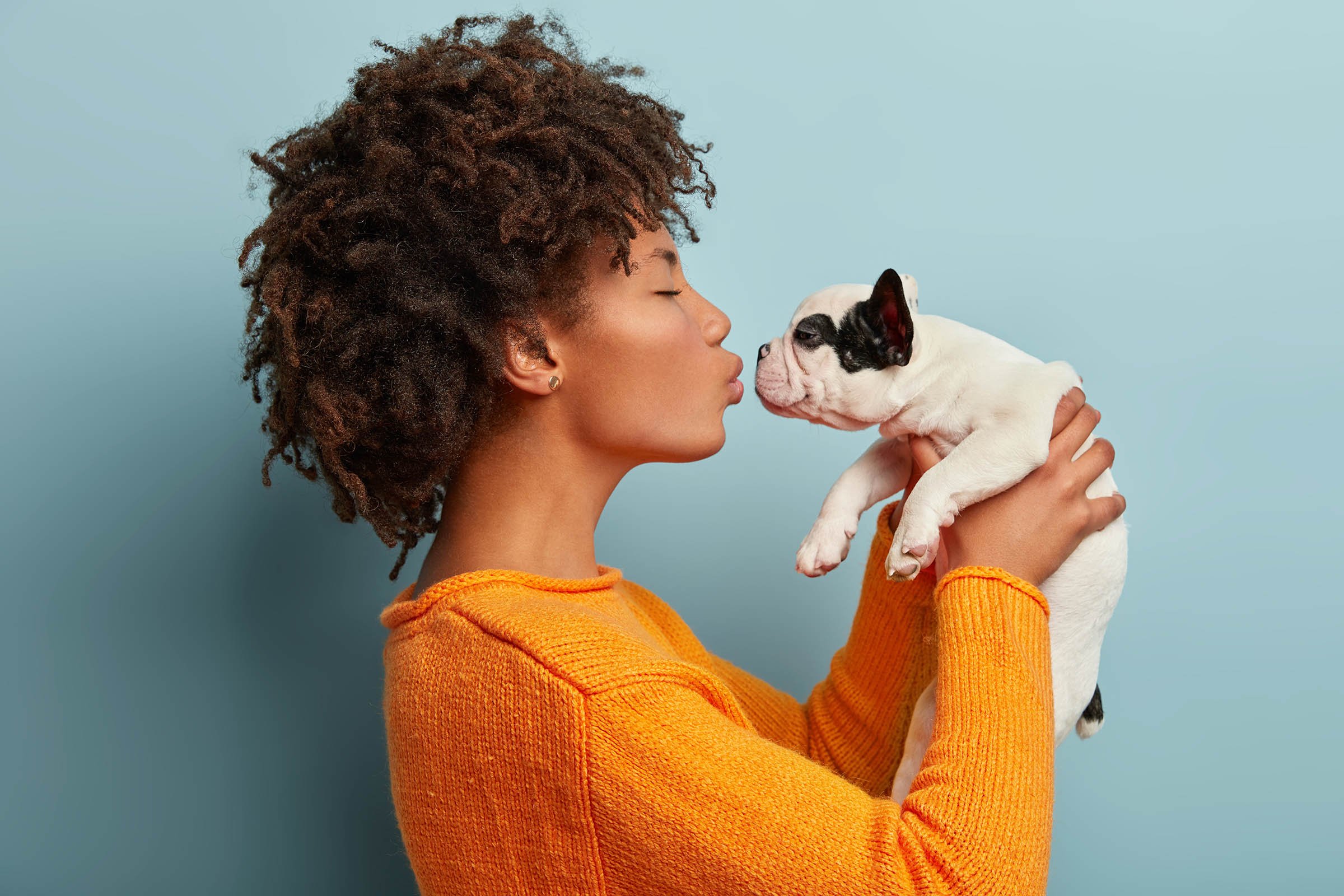 A woman holding up and about to kiss a puppy