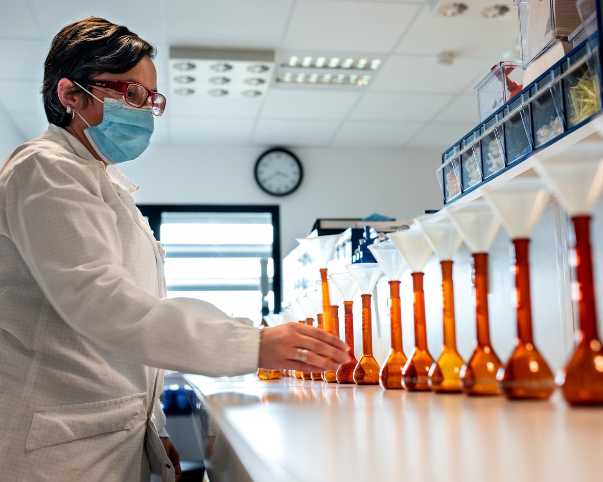 A scientist in a lab with lined up beakers