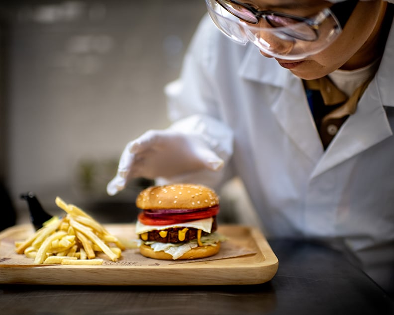 A scientist carefully inspecting a burger and fries