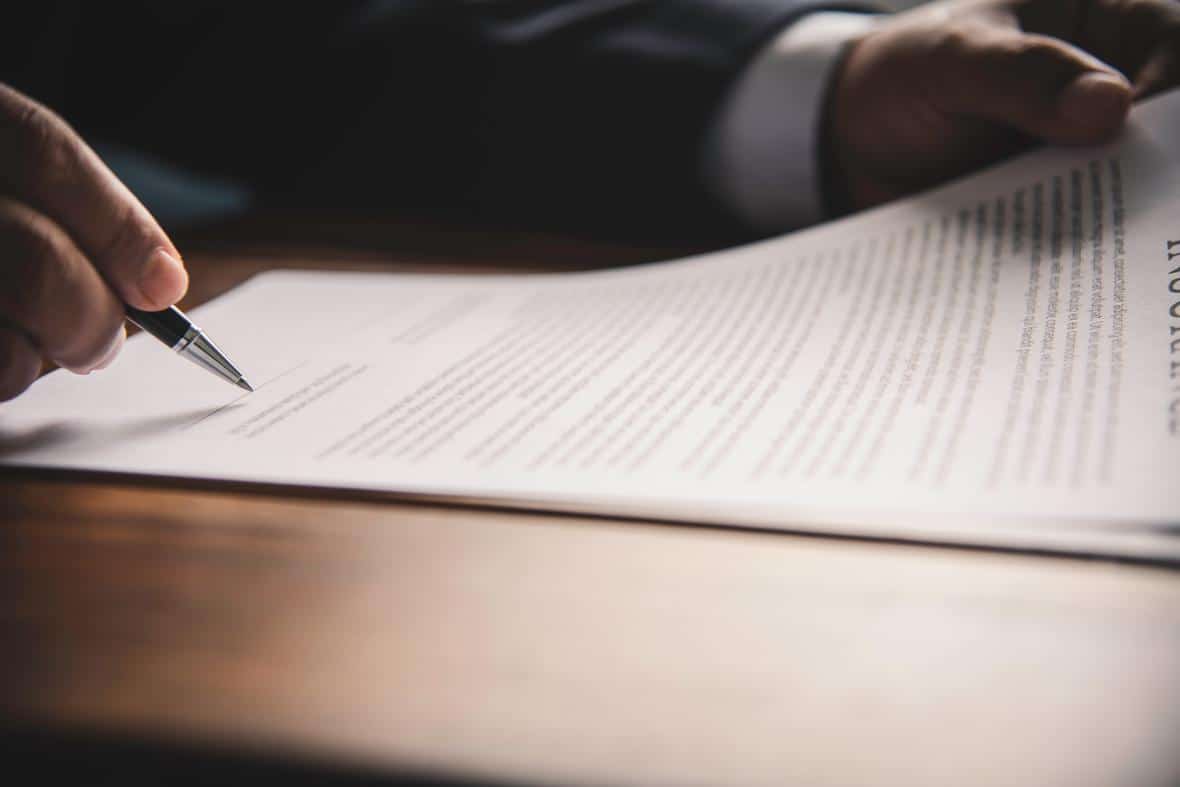 A hand holding a pen signing a contract