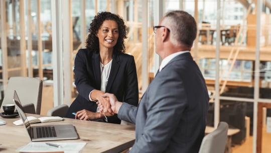 man in woman shaking hands in office