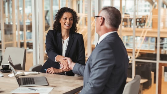 man in woman shaking hands in office