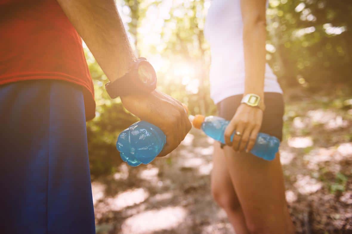 Couple hiking in woods with blue sports drinks