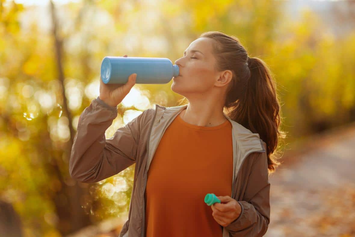 Woman on nature walk drinking health beverage