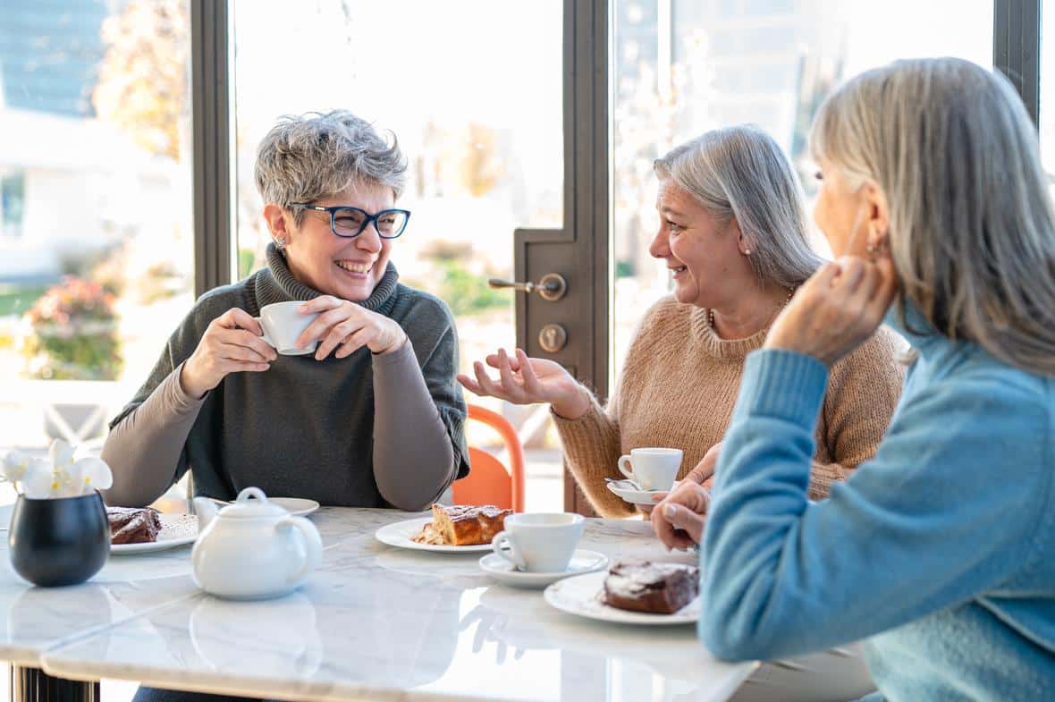 Old women at a table similing while sipping tea