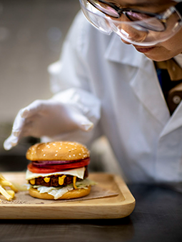 A woman scientist in a white coat grabbing a meat alternative burger