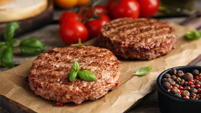 Close up of raw, tasty looking plant-based burgers on a black plate