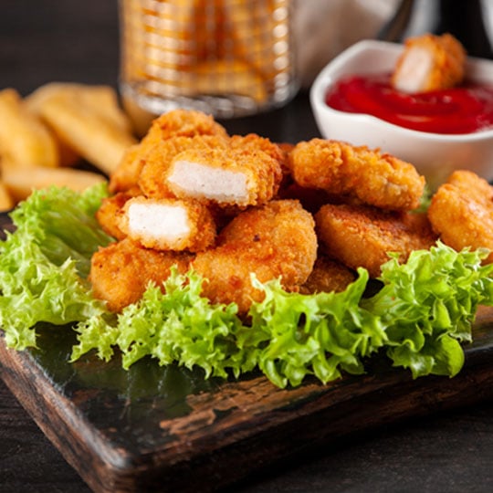 Close up of tasty plant-based nuggets on a big plate with green salad