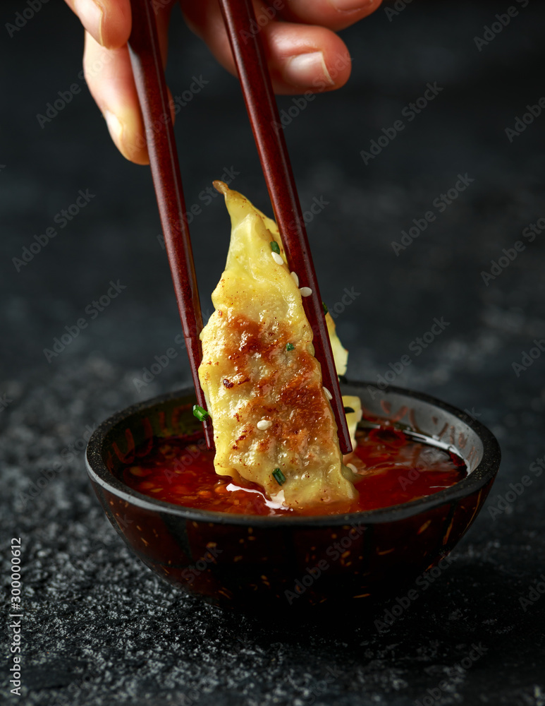 An Asian dumpling is poured into a sauce
