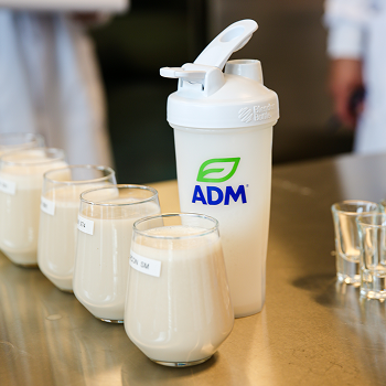 Glasses of protein shake next to an ADM-branded shaker bottle