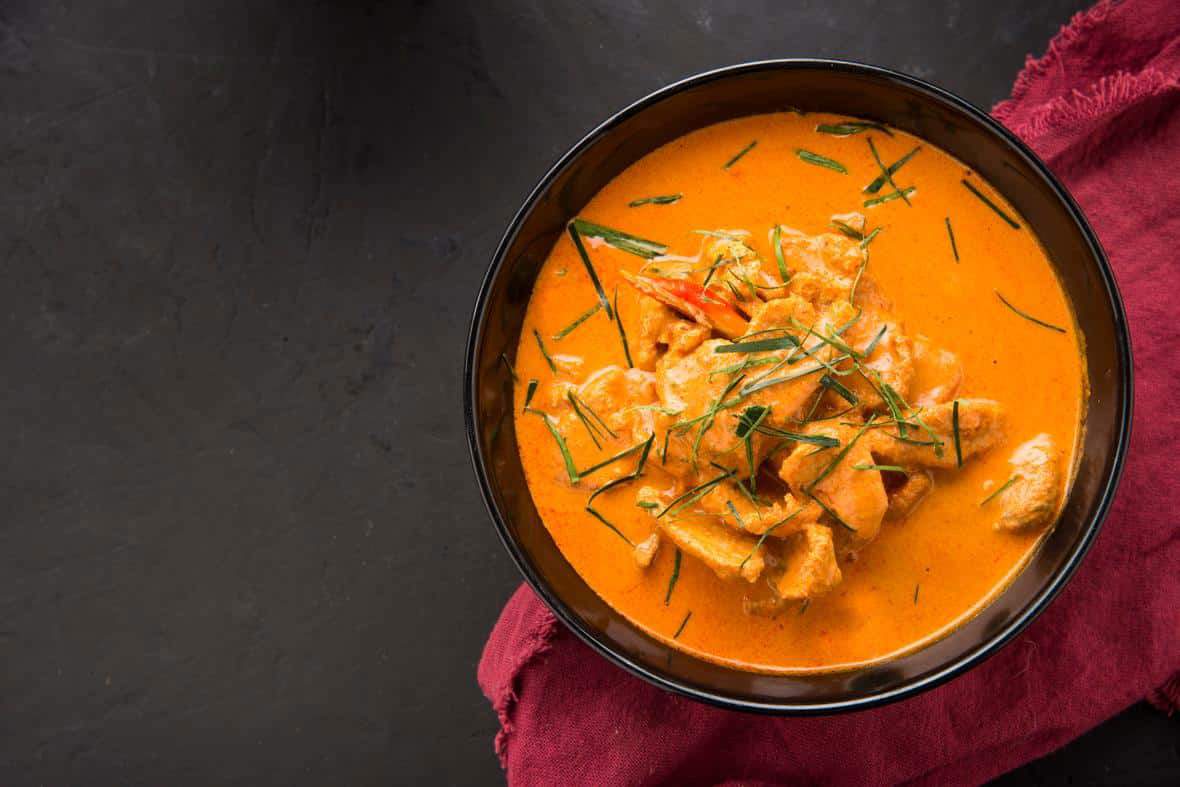 Pot of orange curry with plant based meat on black background