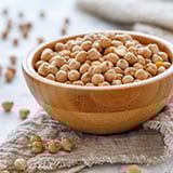 A wooden bowl of uncooked chickpeas