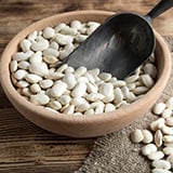 A bowl of white beans with a scoop