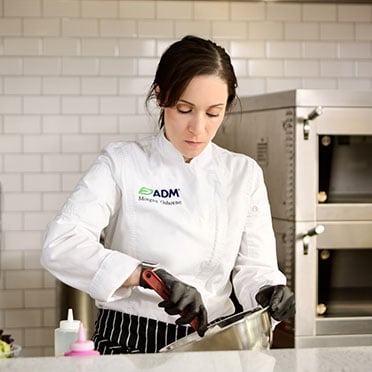 A person wearing an ADM-branded chef’s coat