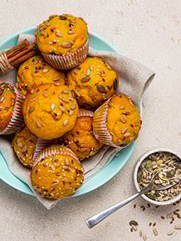A bowl of muffins with cinnamon sticks and a napkin