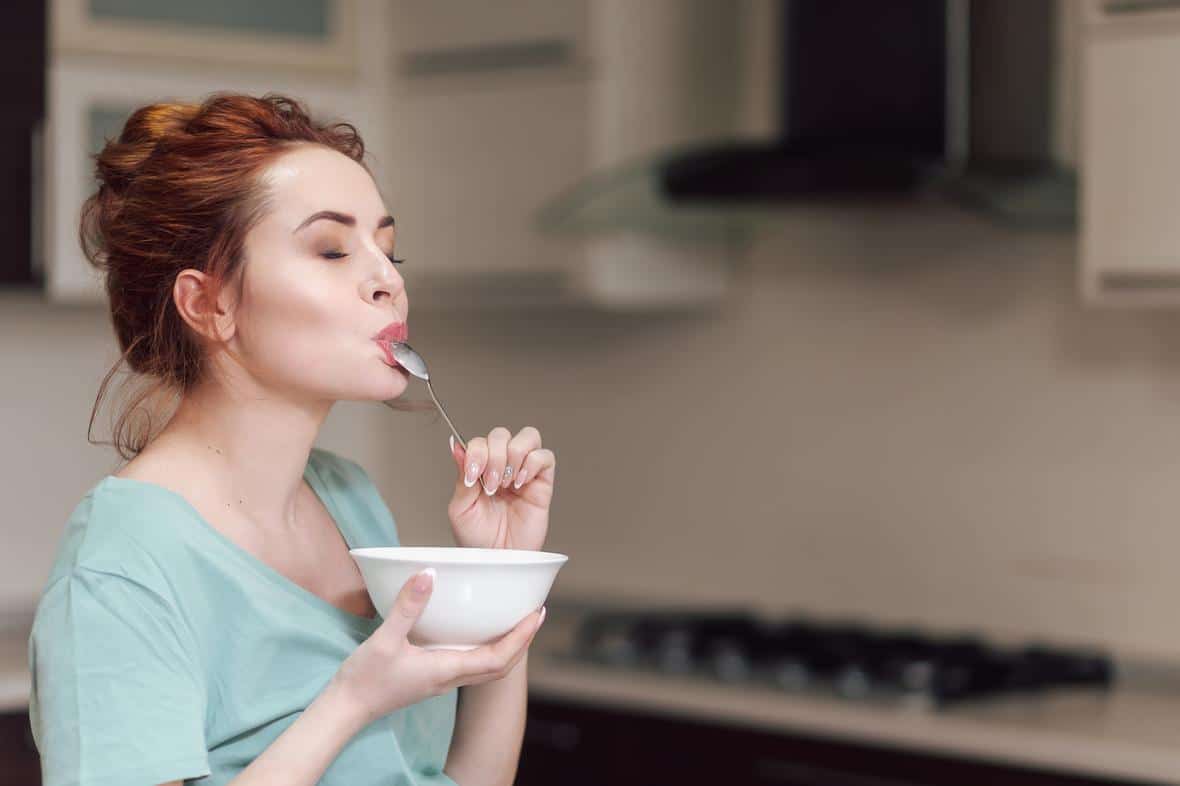 Woman eating delicious cereal with eyes closed as she takes a bite