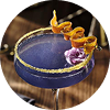 A purple cocktail in a coupe glass with garnishes