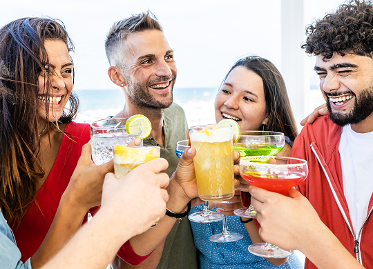A group of people gathered together and toasting with brightly colored beverages