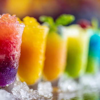 A row of rainbow-colored slushie drinks made with naturally derived color solutions