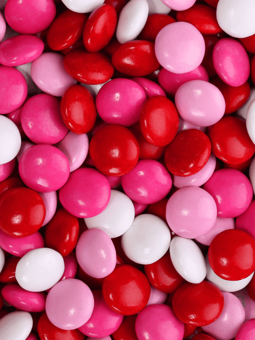 Coated candy in various shades of naturally derived reds and pinks