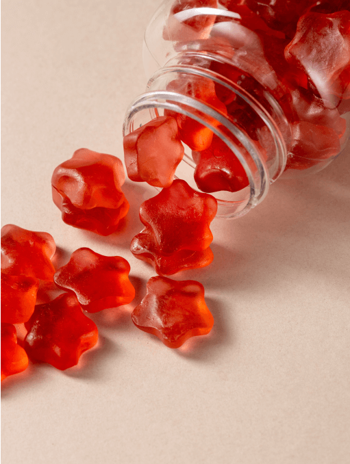 Red gummy supplements spilling out of a bottle