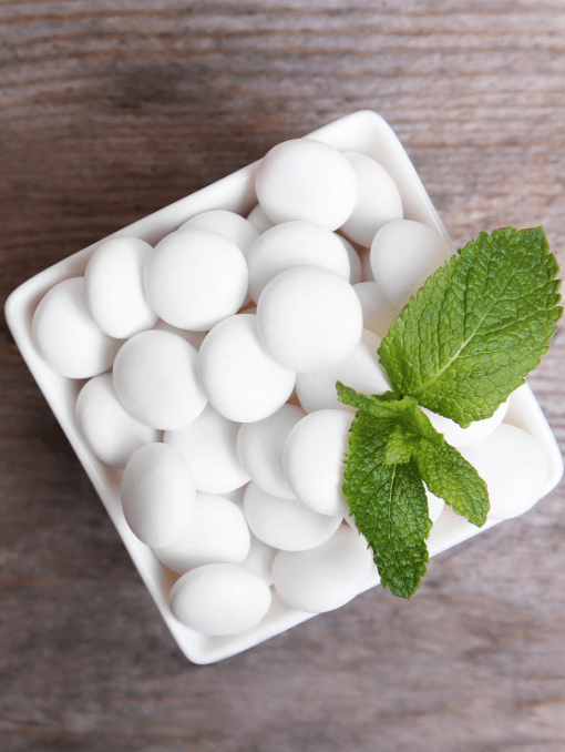 A square, white dish of white mint candies