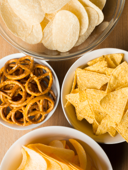 White bowls with pretzels, corn chips, and crisps