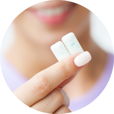 A person holding two pieces of white square chewing gum close to the camera