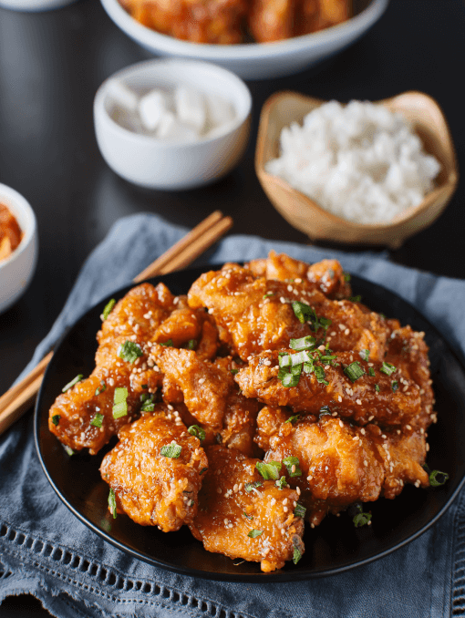 Crispy fried Korean chicken wings in galbi sauce with pickled radish, kimchi, and rice side dishes