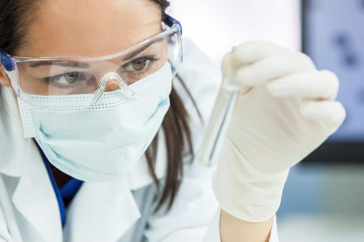 A scientist examining pharmaceutical oil in a test tube