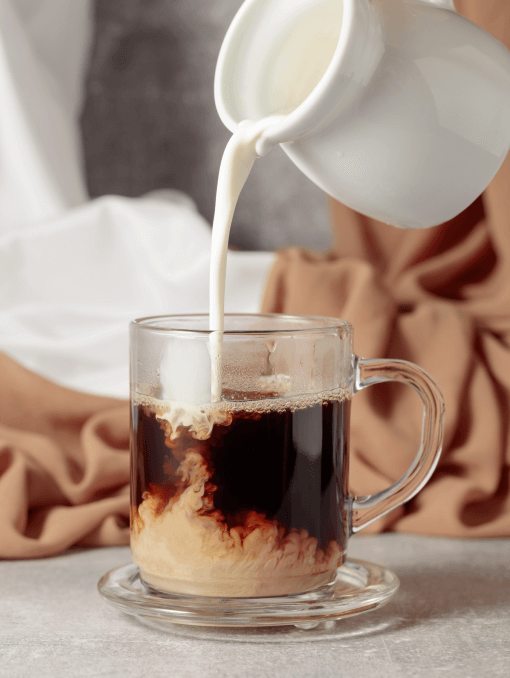 Creamer being poured into a cup of coffee