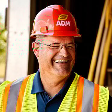 A man wearing an ADM-branded hard hat and reflective safety vest