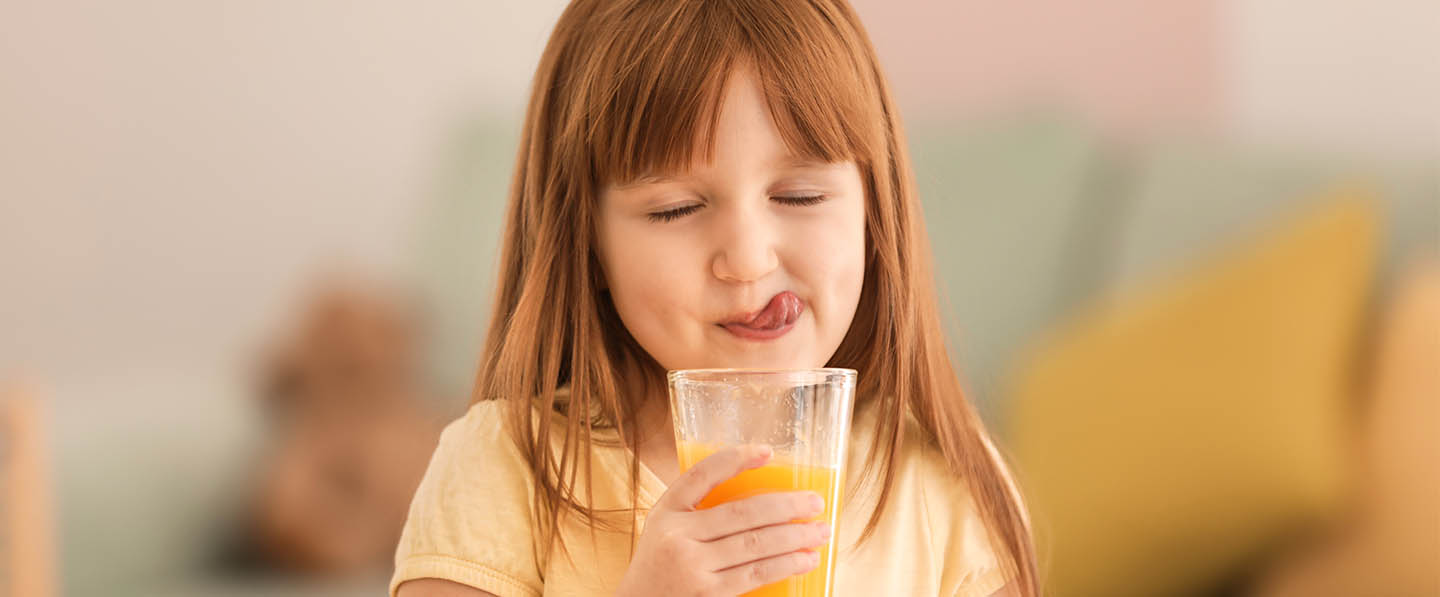 Little girl drinking a delicious orange juice